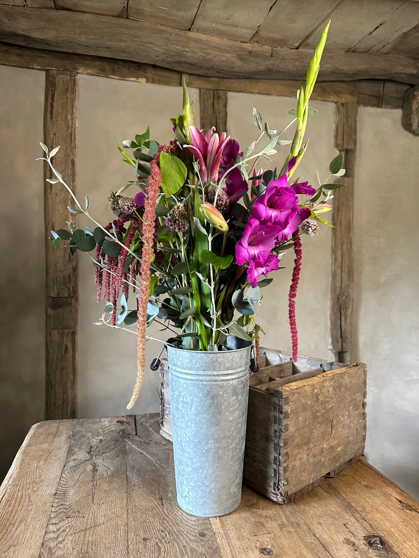 Floral arrangement in a metal bucket on a wooden table with a rustic background