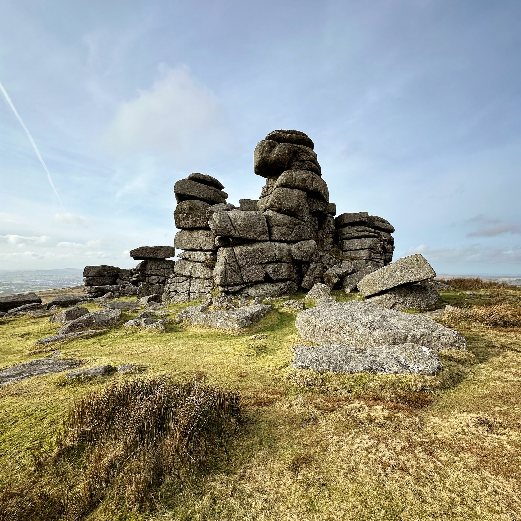 Large stone formation on a grassy hill with a clear sky