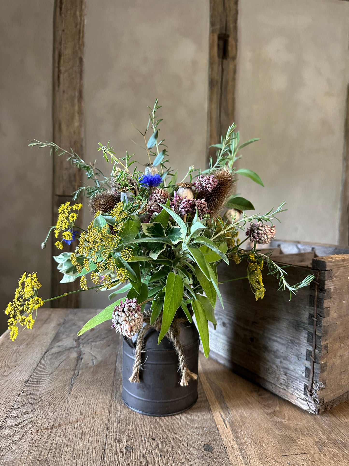 Bouquet of wildflowers in a black pot on a wooden floor with a rustic background
