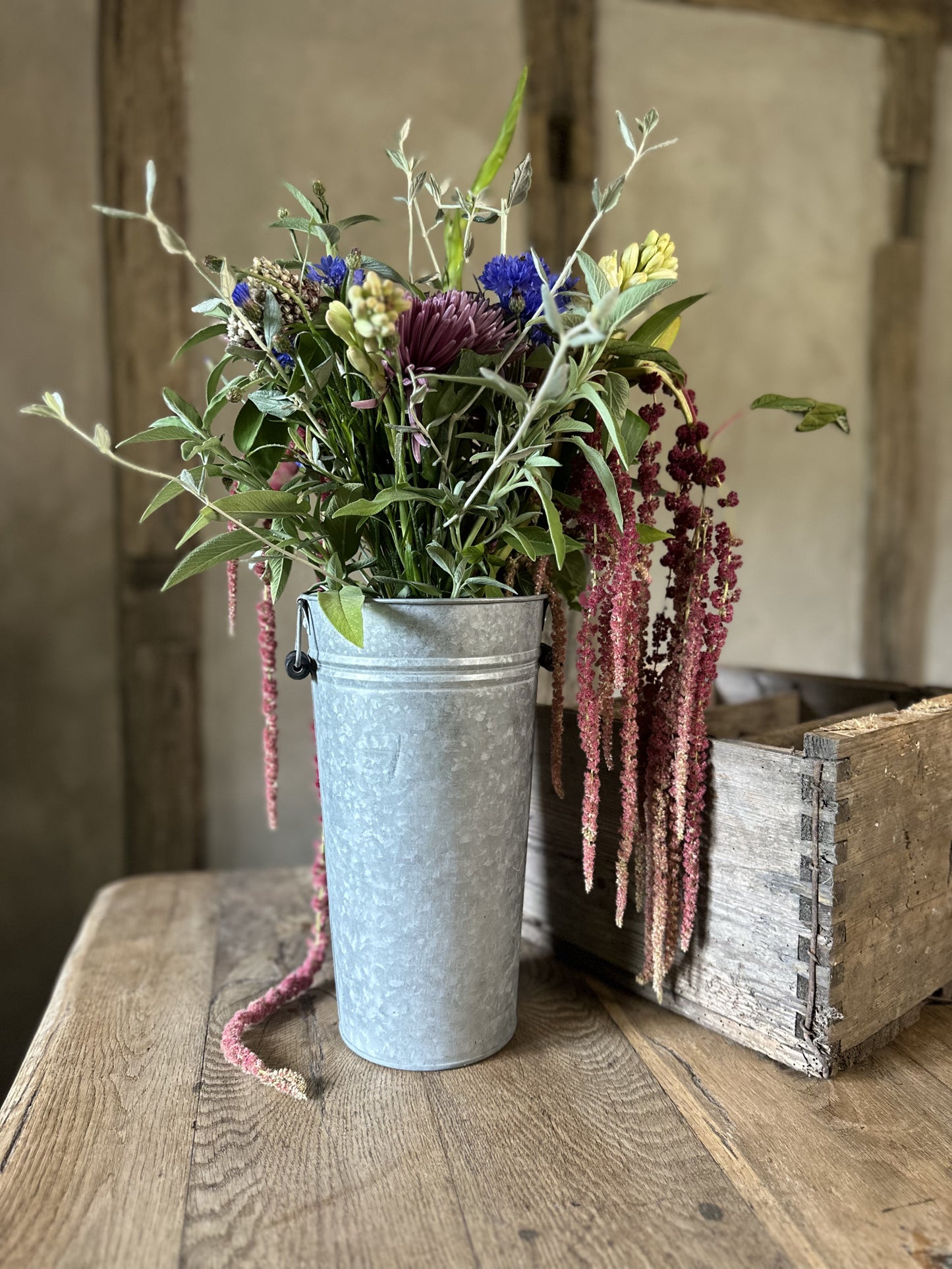 Metal bucket with a bouquet of flowers on a wooden surface