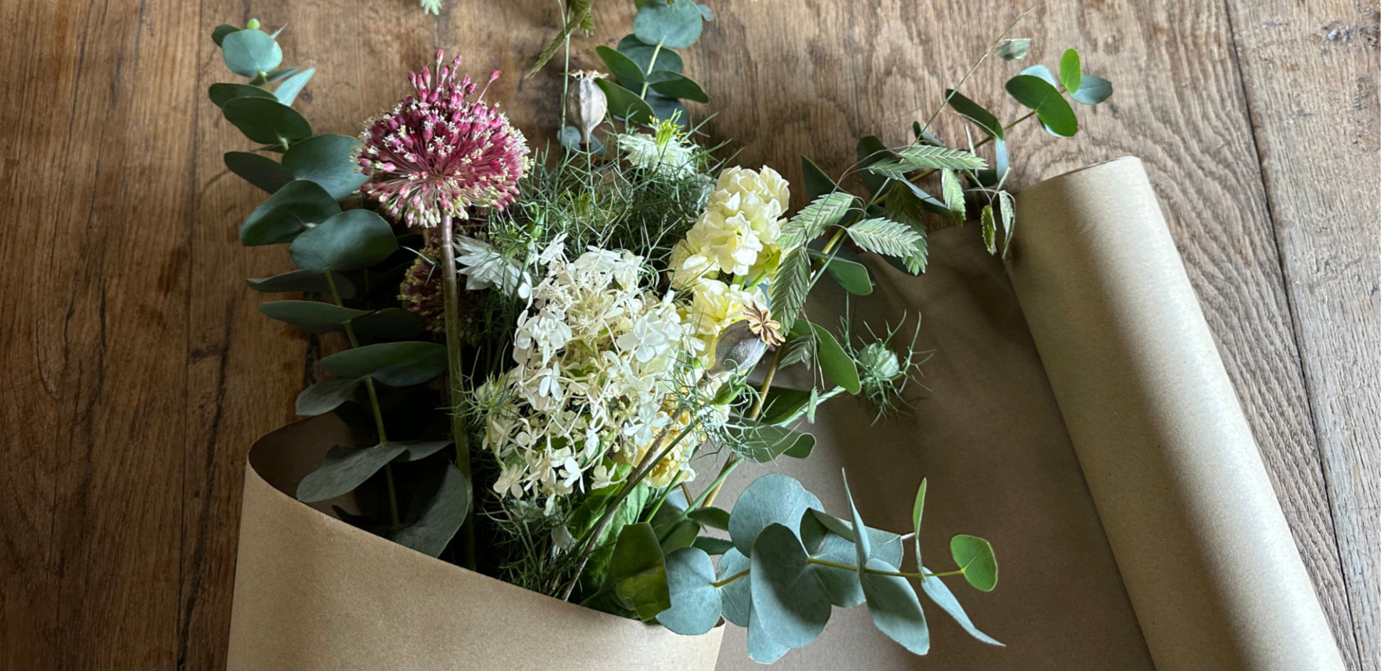Bouquet of flowers wrapped in brown paper on a wooden surface